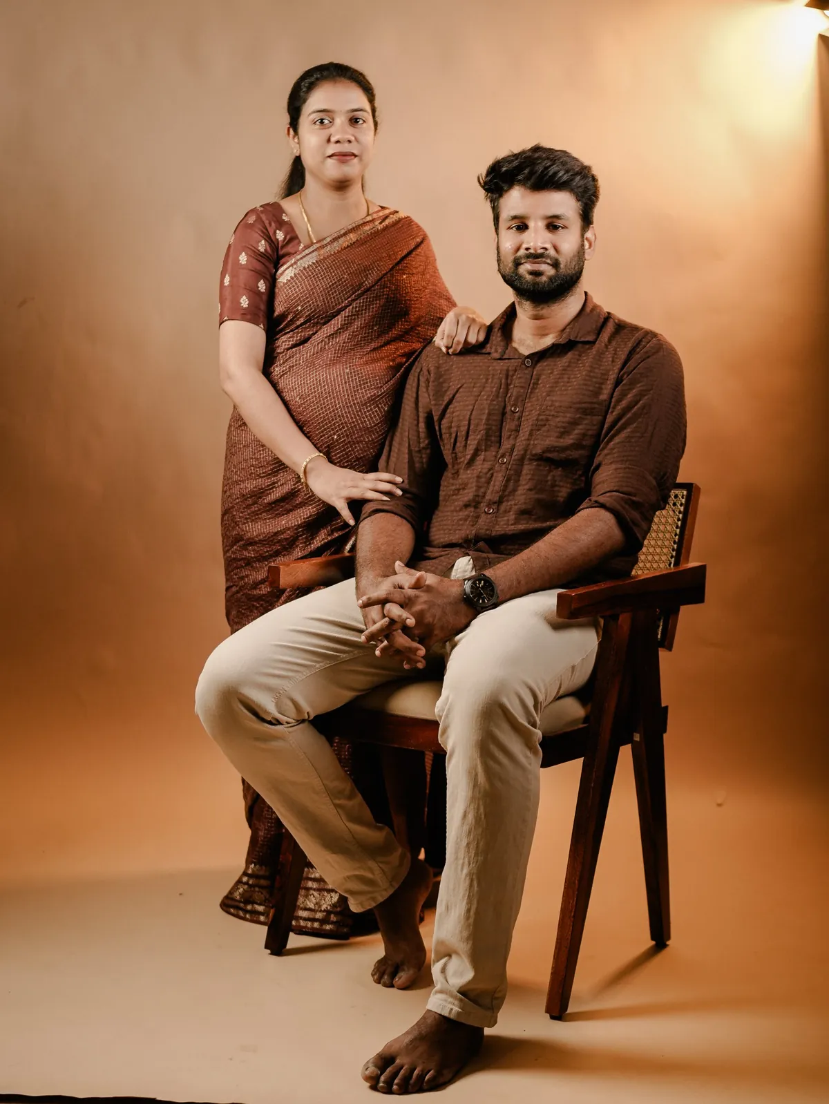 The same couple in brown, lit by a warm studio light that turns the backdrop amber.