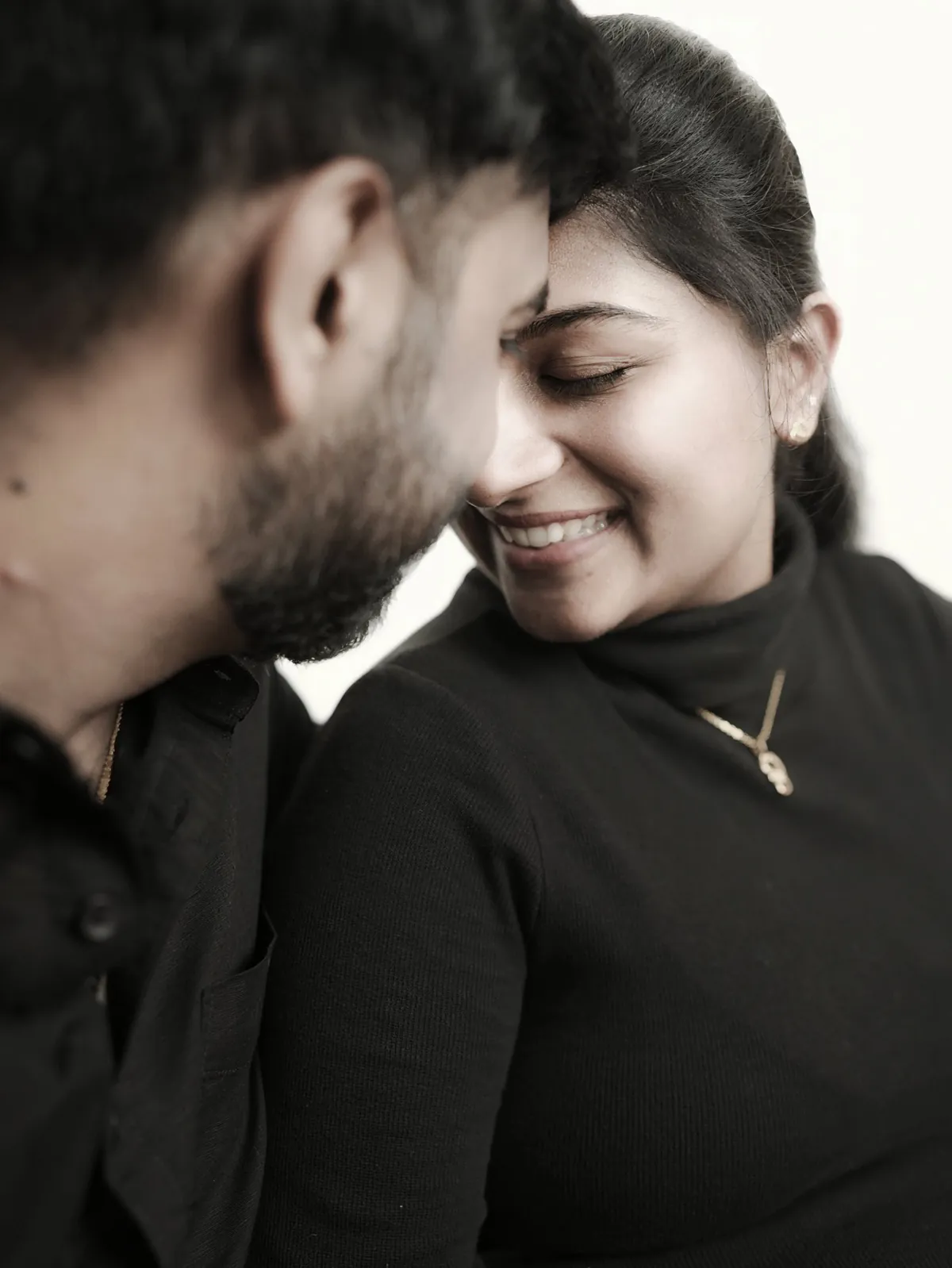 Soft close-up of a couple resting their foreheads together; she smiles with her eyes closed.
