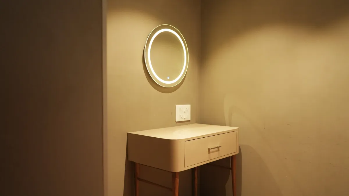 A vanity table with a drawer beneath a round, ring-lit mirror in the makeup room.